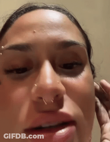 A Close Up Of A Woman 'S Face With A Piercing In Her Nose . GIF