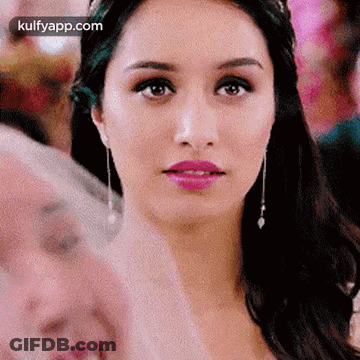 A Close Up Of A Woman 'S Face With A Pink Lip And Earrings . GIF