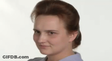 A Close Up Of A Woman 'S Face With A Ponytail And A Blue Shirt . GIF