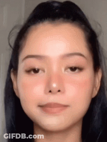 A Close Up Of A Woman 'S Face With A Ponytail And A Red Cheek . GIF