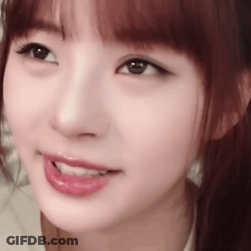 A Close Up Of A Woman 'S Face With A Ponytail And A Smile On Her Face . GIF