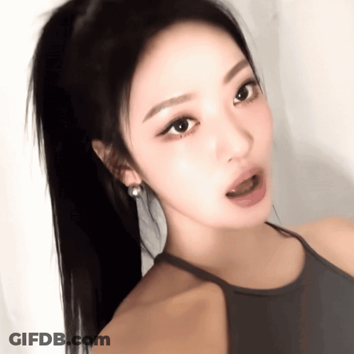 A Close Up Of A Woman 'S Face With A Ponytail And Earrings GIF