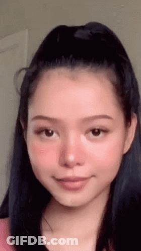 A Close Up Of A Woman 'S Face With A Ponytail And Pink Blush . GIF