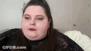 A Close Up Of A Woman 'S Face With A Ponytail And Pink Earrings . GIF