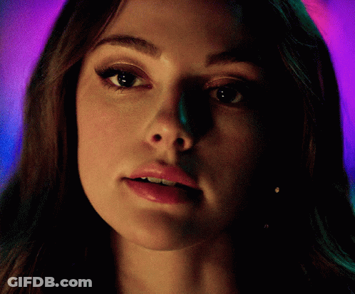 A Close Up Of A Woman 'S Face With A Purple And Green Background GIF