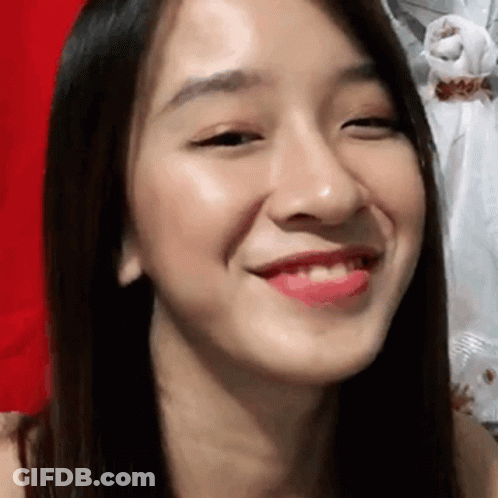 A Close Up Of A Woman 'S Face With A Red Background And A Smile On Her Face . GIF