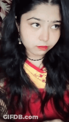 A Close Up Of A Woman 'S Face With A Red Shirt And Yellow Scarf GIF