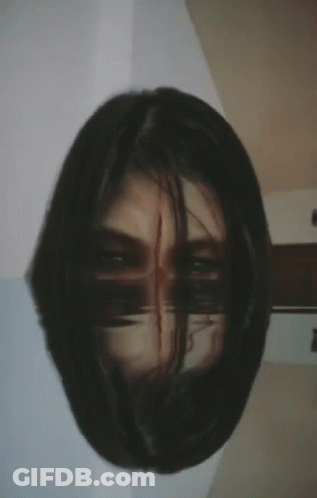 A Close Up Of A Woman 'S Face With A Reflection Of Her Face In The Mirror GIF