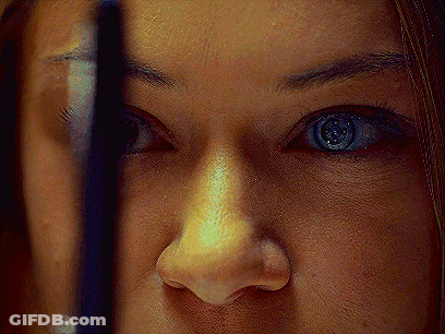 A Close Up Of A Woman 'S Face With A Reflection Of Herself In The Mirror GIF
