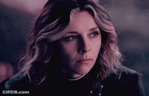 A Close Up Of A Woman 'S Face With A Serious Look On Her Face In A Dark Room . GIF