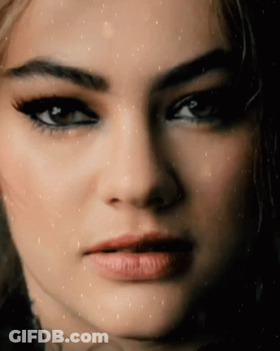 A Close Up Of A Woman 'S Face With A Slight Smile On Her Face GIF