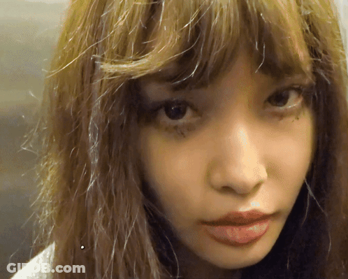 A Close Up Of A Woman 'S Face With A Slight Smirk GIF