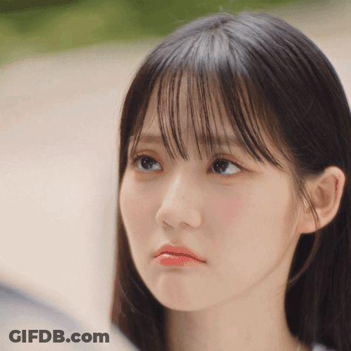 A Close Up Of A Woman 'S Face With A Slight Smirk On Her Face GIF