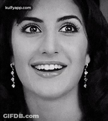 A Close Up Of A Woman 'S Face With A Smile And Earrings . GIF