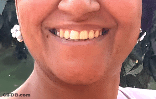 A Close Up Of A Woman 'S Face With A Smile And Earrings GIF