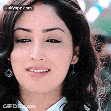 A Close Up Of A Woman 'S Face With A Smile On Her Face And Earrings . GIF