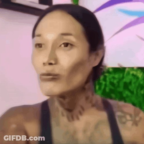 A Close Up Of A Woman 'S Face With A Tattoo On Her Neck GIF