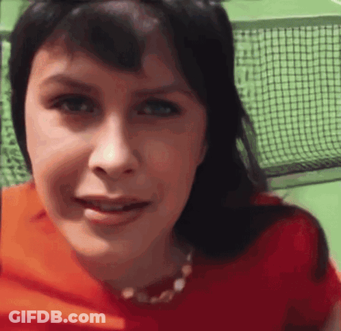 A Close Up Of A Woman 'S Face With A Tennis Net Behind Her GIF