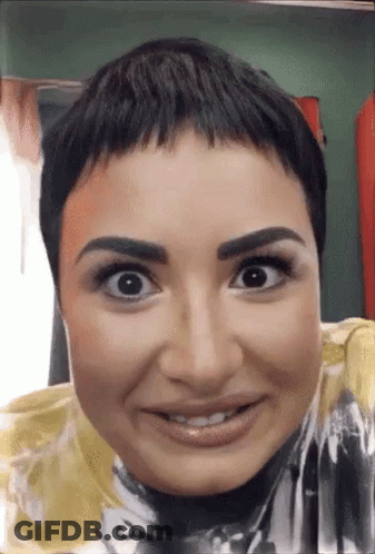 A Close Up Of A Woman 'S Face With A Very Short Haircut . GIF