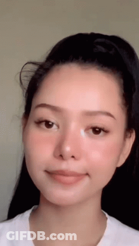 A Close Up Of A Woman 'S Face With A White Shirt On . GIF