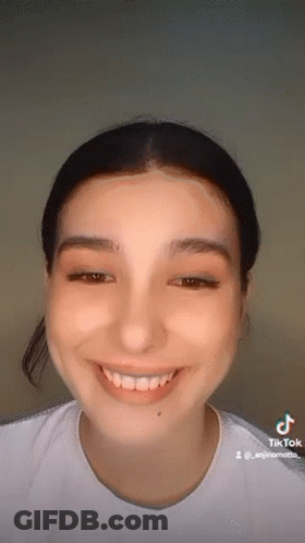 A Close Up Of A Woman 'S Face With A White Shirt On Smiling . GIF