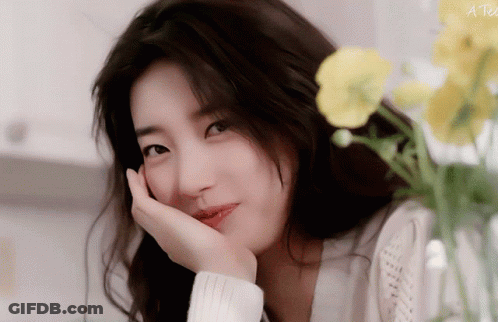 A Close Up Of A Woman 'S Face With A Yellow Flower In The Background And The Words A Tea On The Bottom Right GIF
