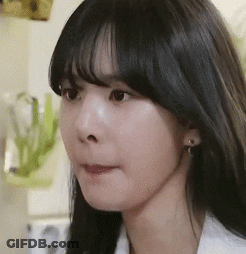 A Close Up Of A Woman 'S Face With Black Hair And Earrings . GIF