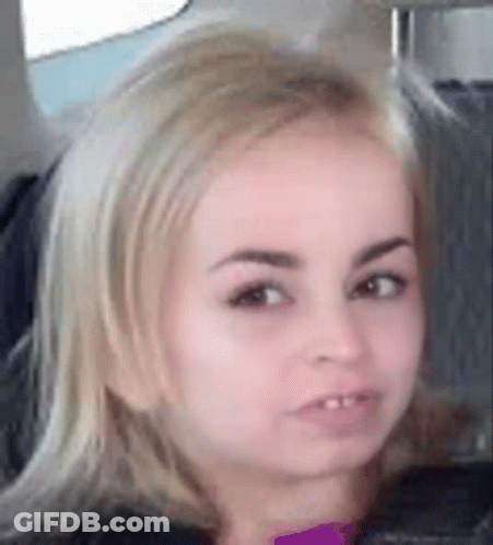 A Close Up Of A Woman 'S Face With Blonde Hair And A Purple Shirt . GIF