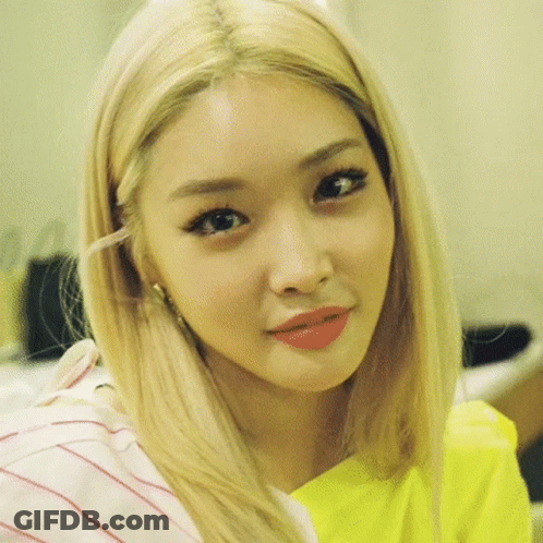 A Close Up Of A Woman 'S Face With Blonde Hair And A Yellow Shirt . GIF