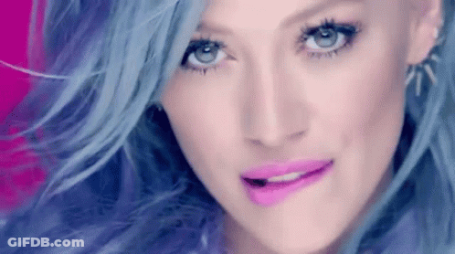 A Close Up Of A Woman 'S Face With Blue Hair And Pink Lips GIF