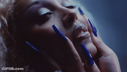 A Close Up Of A Woman 'S Face With Blue Long Nails GIF