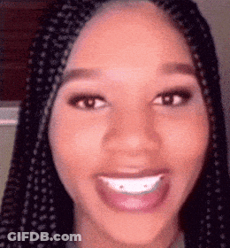 A Close Up Of A Woman 'S Face With Braids And A Big Smile . GIF