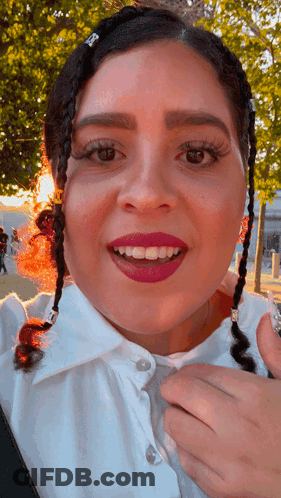 A Close Up Of A Woman 'S Face With Braids In Her Hair And A White Shirt GIF