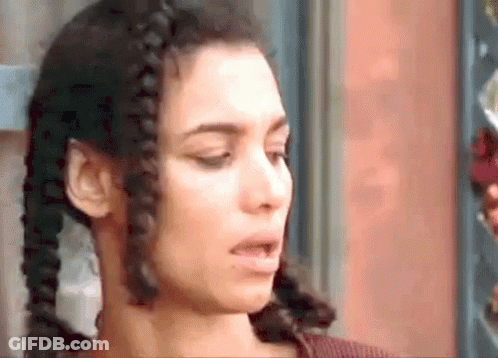 A Close Up Of A Woman 'S Face With Braids In Her Hair Making A Funny Face . GIF