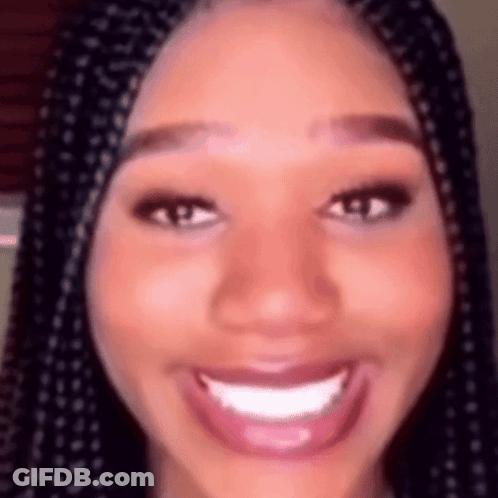 A Close Up Of A Woman 'S Face With Braids Smiling And Looking At The Camera . GIF