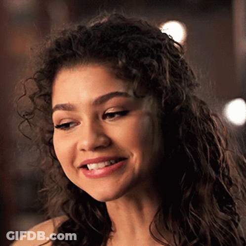 A Close Up Of A Woman 'S Face With Curly Hair . GIF