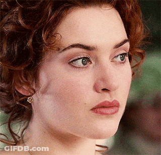 A Close Up Of A Woman 'S Face With Curly Hair And Green Eyes GIF
