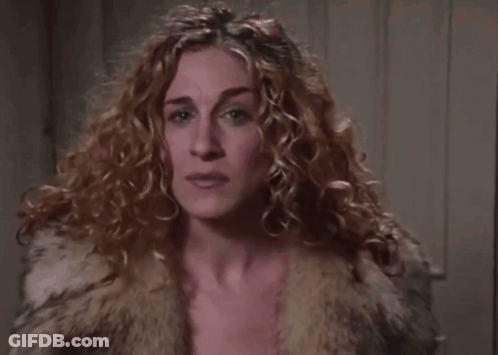 A Close Up Of A Woman 'S Face With Curly Hair Wearing A Fur Coat . GIF