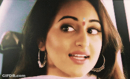 A Close Up Of A Woman 'S Face With Earrings And A Red Dot On Her Forehead GIF
