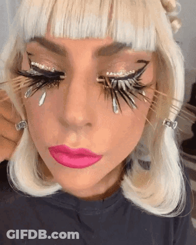 A Close Up Of A Woman 'S Face With Feathered Eyelashes And Pink Lips GIF
