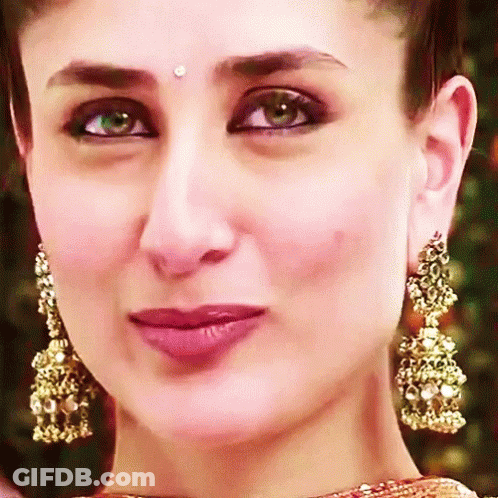 A Close Up Of A Woman 'S Face With Gold Earrings GIF