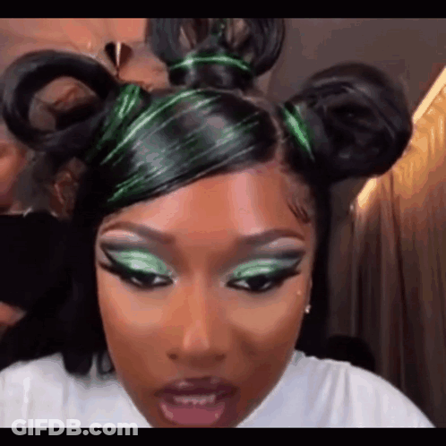 A Close Up Of A Woman 'S Face With Green Eye Shadow And A Bun In Her Hair . GIF