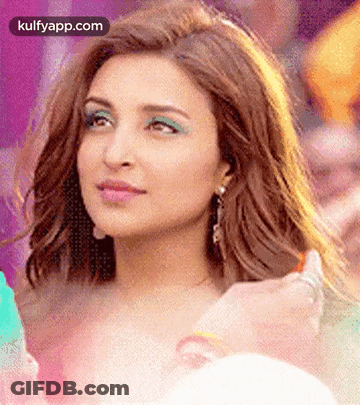 A Close Up Of A Woman 'S Face With Green Eye Shadow And Earrings . GIF