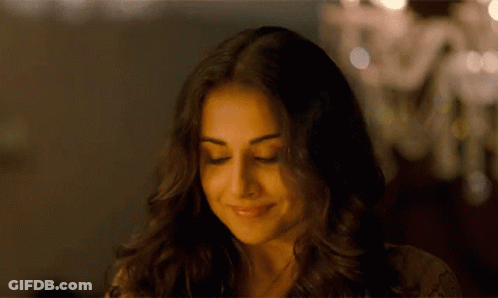 A Close Up Of A Woman 'S Face With Her Eyes Closed And A Chandelier In The Background . GIF