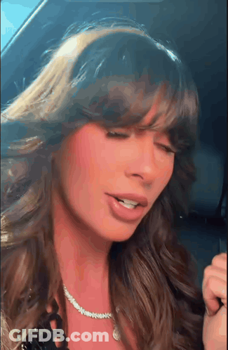 A Close Up Of A Woman 'S Face With Her Eyes Closed And A Necklace Around Her Neck . GIF