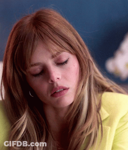 A Close Up Of A Woman 'S Face With Her Eyes Closed And A Yellow Jacket On GIF