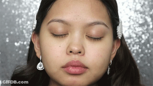 A Close Up Of A Woman 'S Face With Her Eyes Closed And Earrings GIF