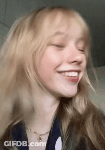 A Close Up Of A Woman 'S Face With Her Eyes Closed And Smiling . GIF