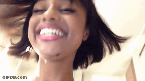 A Close Up Of A Woman 'S Face With Her Eyes Closed And Smiling . GIF