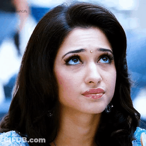 A Close Up Of A Woman 'S Face With Her Eyes Looking Up . GIF
